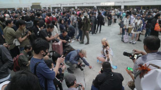 囲み撮影しながら名刺も手に取るカメラマン