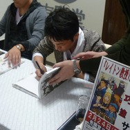 ナルホドくんのイラスト入りサインを1冊1冊丁寧に描いていく塗氏